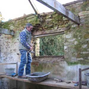 maçon travaille sur mur du gîte
